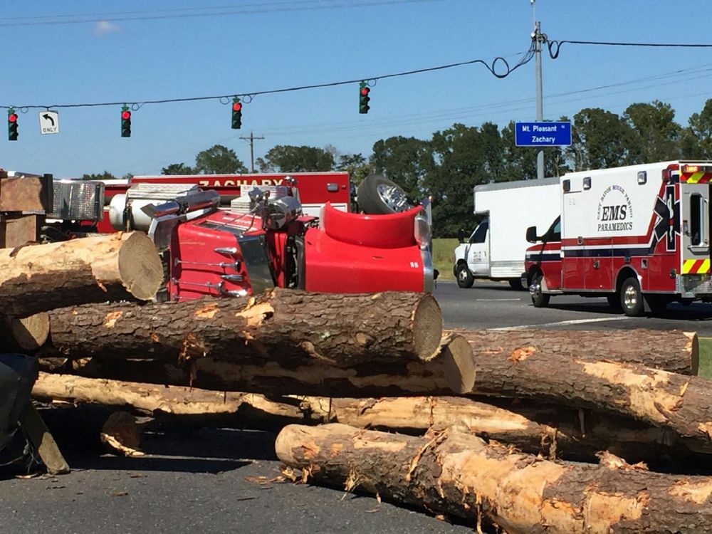 Pickup crushed by logs from overturned log truck